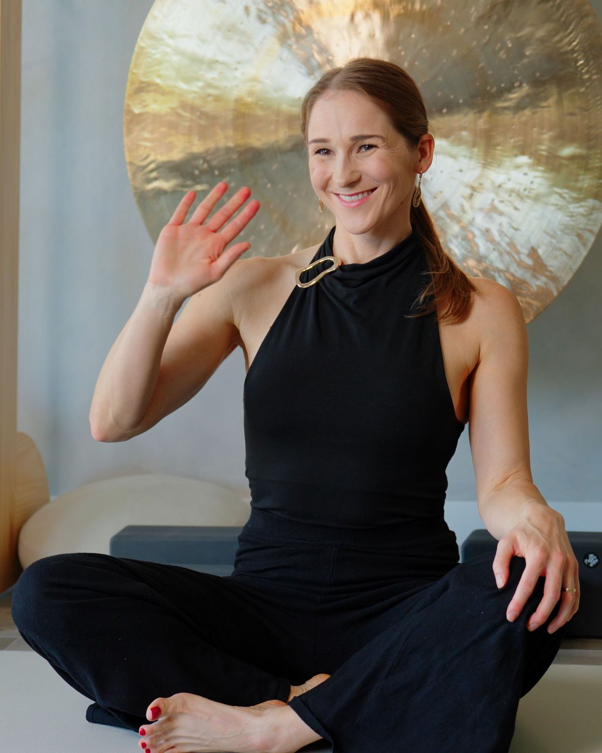 Liz Adriano, founder of Incendify, waving a warm welcome from the studio where she films her online professional development courses for leaders and entrepreneurs
